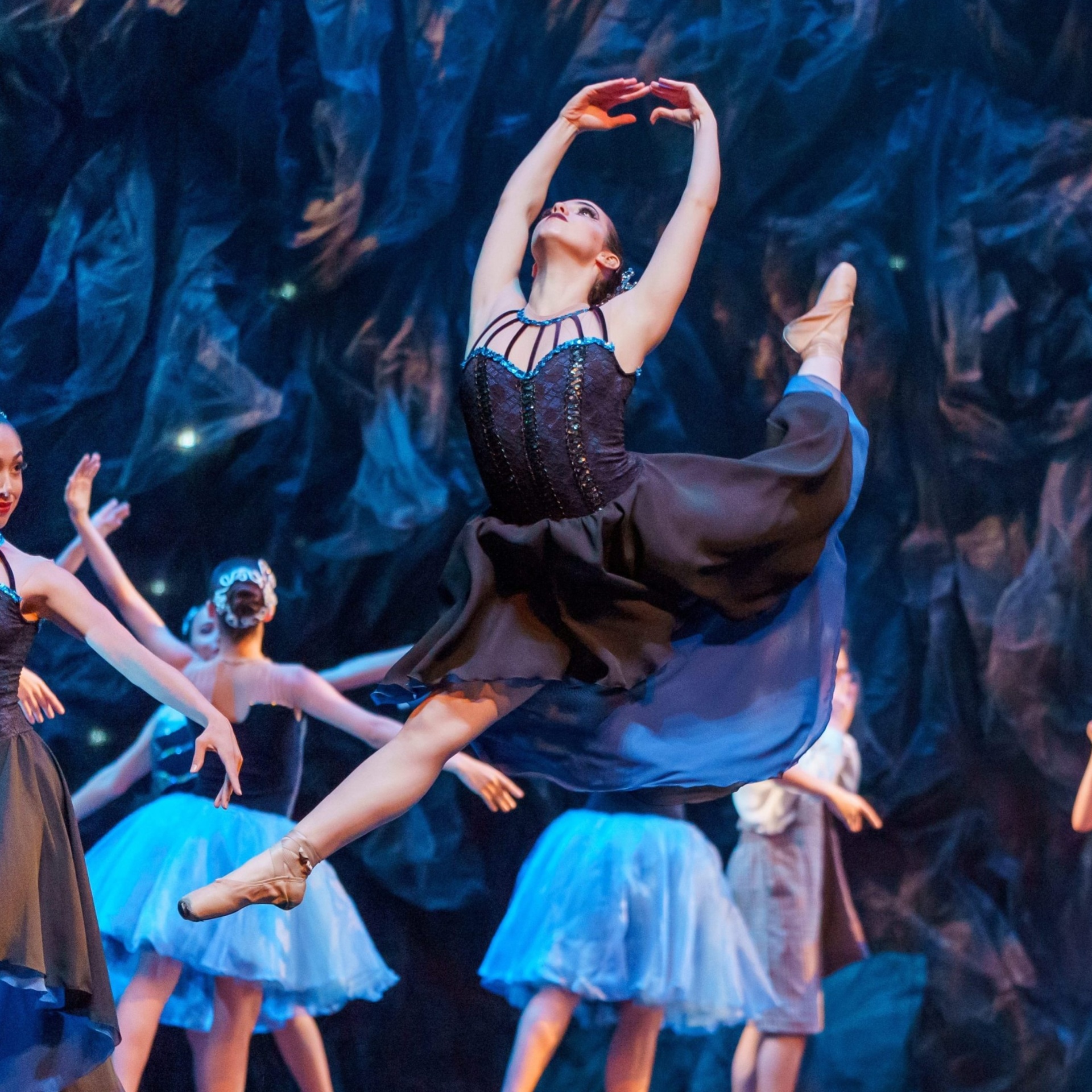 Bailarina em salto com pose graciosa em apresentação no palco
